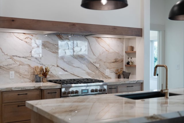 kitchen featuring a sink, light stone counters, backsplash, ventilation hood, and stove