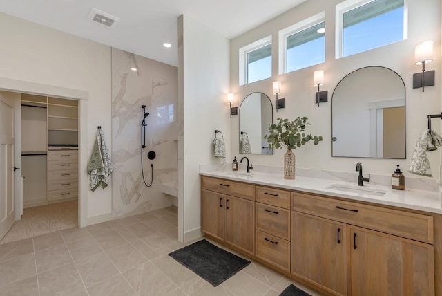 full bathroom featuring double vanity, walk in shower, visible vents, and a sink