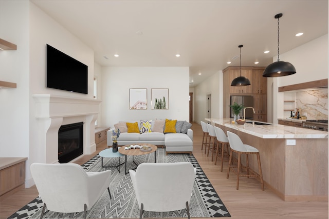 living area featuring recessed lighting, light wood-style flooring, and a glass covered fireplace