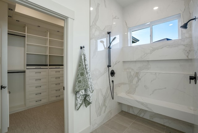 full bathroom featuring a marble finish shower and a walk in closet