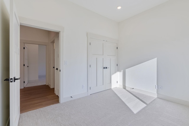 unfurnished bedroom featuring recessed lighting, carpet, baseboards, and a closet