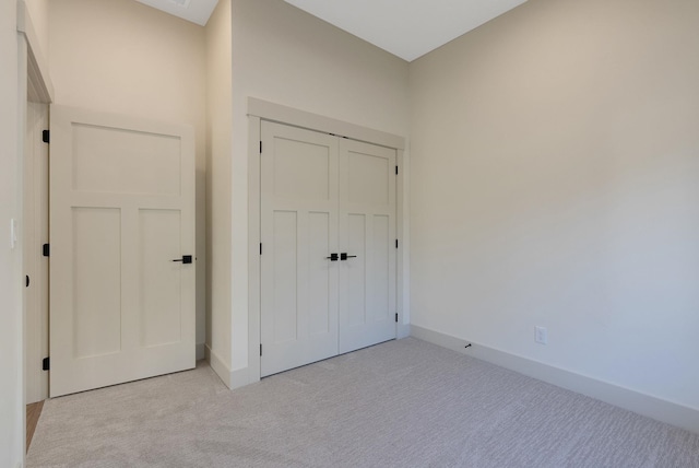 unfurnished bedroom with a closet, baseboards, and light colored carpet