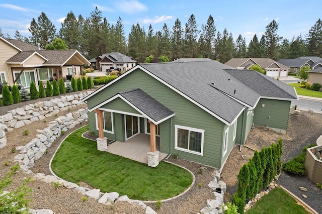 rear view of property with a residential view, a patio, a yard, and a shingled roof