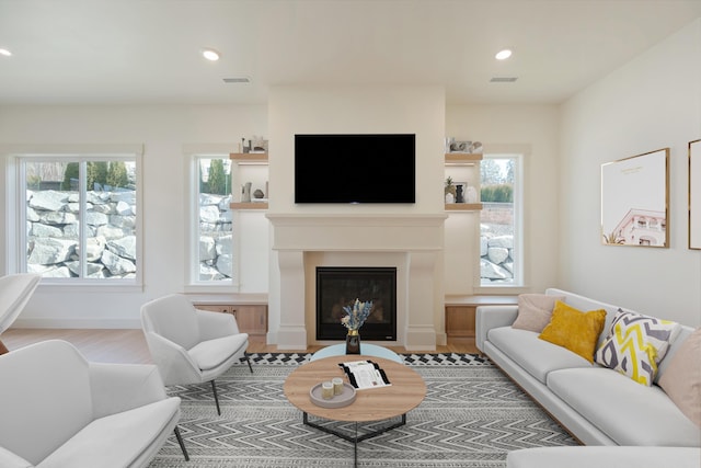 living room with visible vents, a healthy amount of sunlight, and a glass covered fireplace