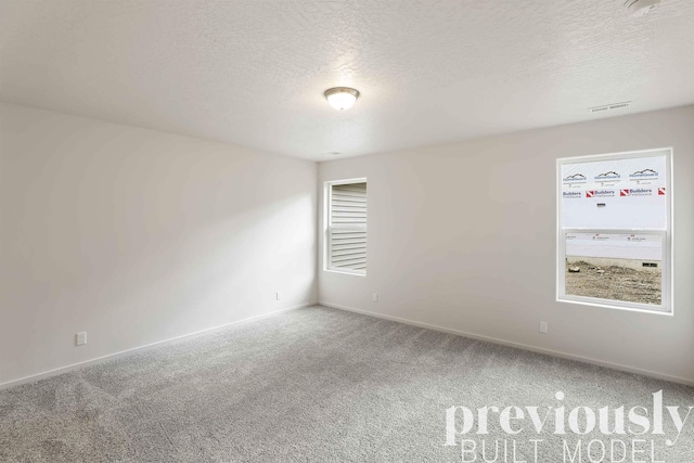 carpeted empty room featuring a textured ceiling