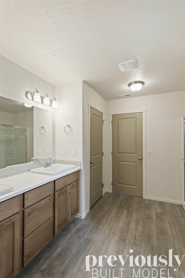 bathroom with hardwood / wood-style floors, vanity, an enclosed shower, and a textured ceiling