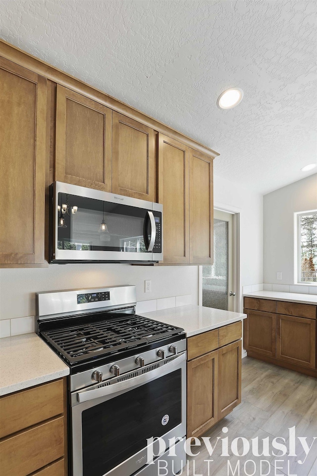 kitchen featuring light hardwood / wood-style flooring, a textured ceiling, and appliances with stainless steel finishes