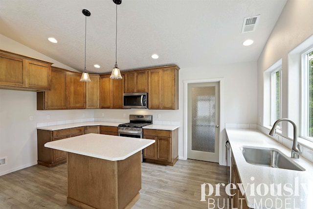 kitchen featuring lofted ceiling, sink, decorative light fixtures, light hardwood / wood-style floors, and stainless steel appliances