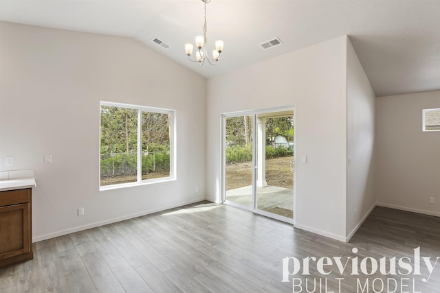 unfurnished dining area featuring light hardwood / wood-style floors, vaulted ceiling, and a chandelier