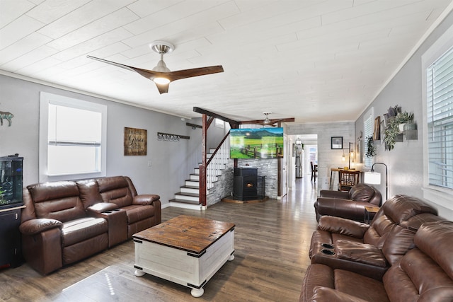 living room featuring hardwood / wood-style floors, a wood stove, ceiling fan, and ornamental molding