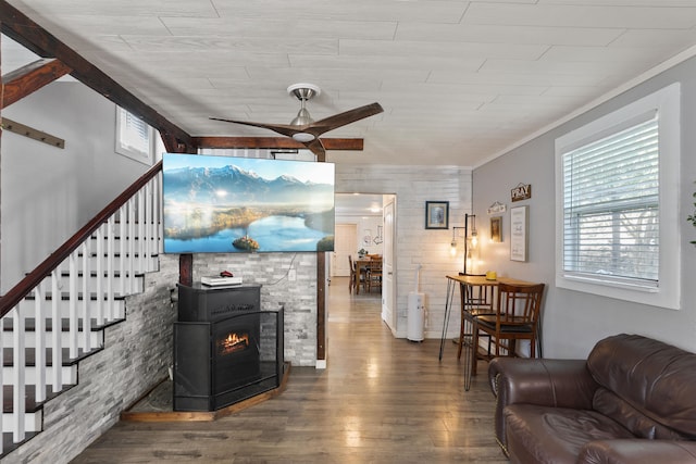 living room with ceiling fan, wood-type flooring, ornamental molding, and a wood stove