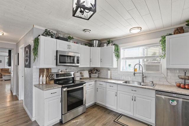 kitchen with appliances with stainless steel finishes, wood ceiling, sink, white cabinets, and light hardwood / wood-style floors