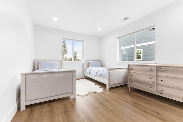 bedroom with wood-type flooring and multiple windows