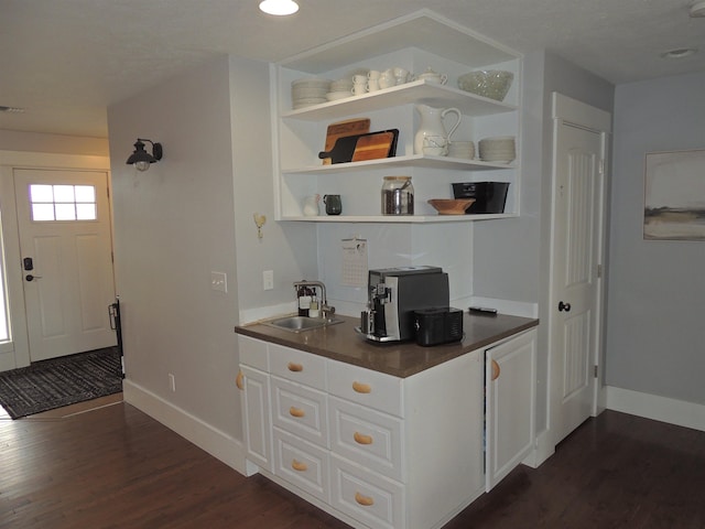 bar with built in shelves, sink, white cabinets, and dark hardwood / wood-style floors