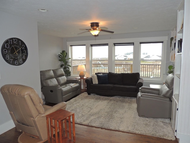 living room featuring ceiling fan and dark wood-type flooring