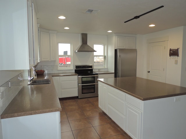 kitchen with a kitchen island, stainless steel appliances, white cabinetry, and wall chimney exhaust hood