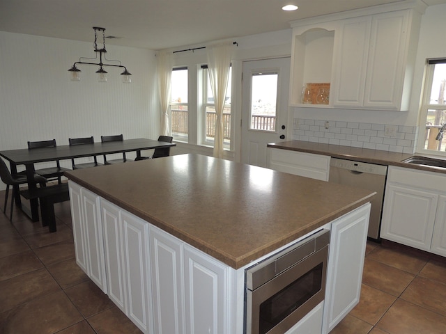 kitchen featuring white cabinets, hanging light fixtures, and appliances with stainless steel finishes