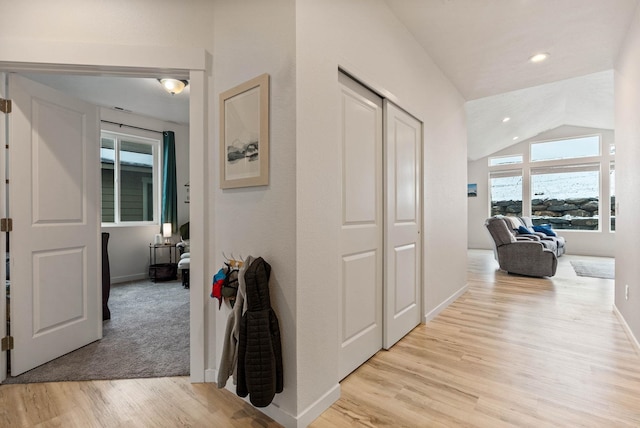 corridor with vaulted ceiling and light hardwood / wood-style flooring