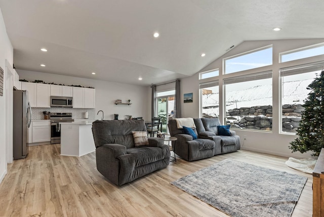 living room featuring sink, vaulted ceiling, and light wood-type flooring