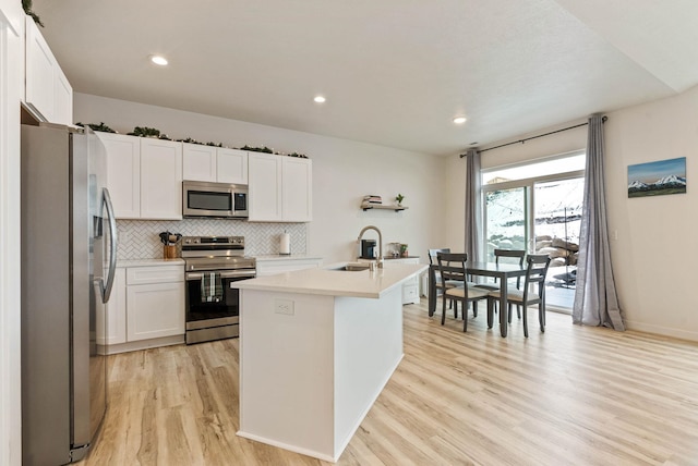 kitchen featuring a center island with sink, white cabinets, sink, appliances with stainless steel finishes, and light hardwood / wood-style floors