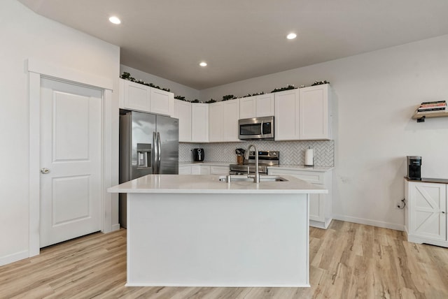 kitchen with a center island with sink, light hardwood / wood-style floors, white cabinetry, and stainless steel appliances