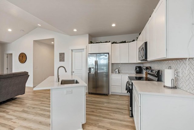 kitchen featuring lofted ceiling, backsplash, a center island with sink, sink, and appliances with stainless steel finishes