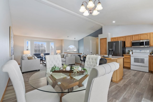 dining space featuring vaulted ceiling with beams, a notable chandelier, and light hardwood / wood-style floors