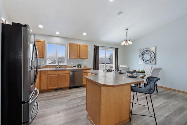 kitchen featuring sink, a center island, light hardwood / wood-style floors, pendant lighting, and appliances with stainless steel finishes