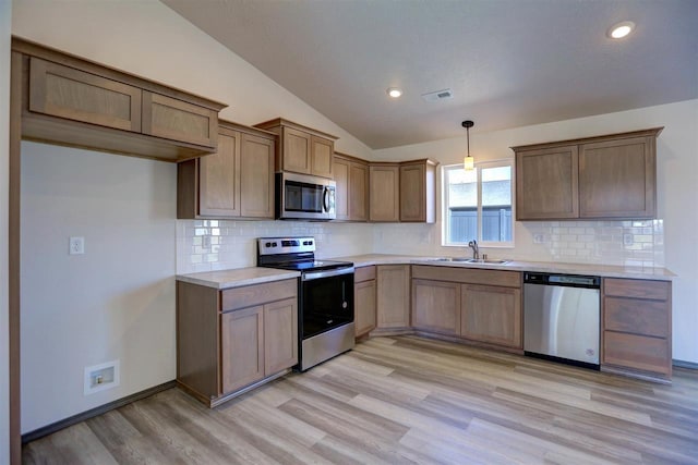 kitchen with appliances with stainless steel finishes, light wood-type flooring, sink, decorative light fixtures, and lofted ceiling