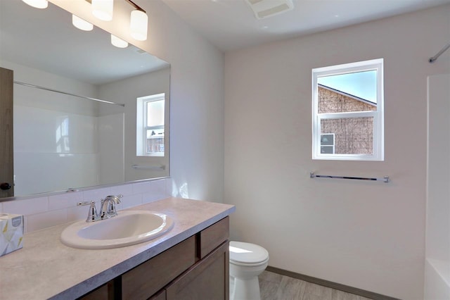 bathroom with backsplash, walk in shower, vanity, hardwood / wood-style flooring, and toilet