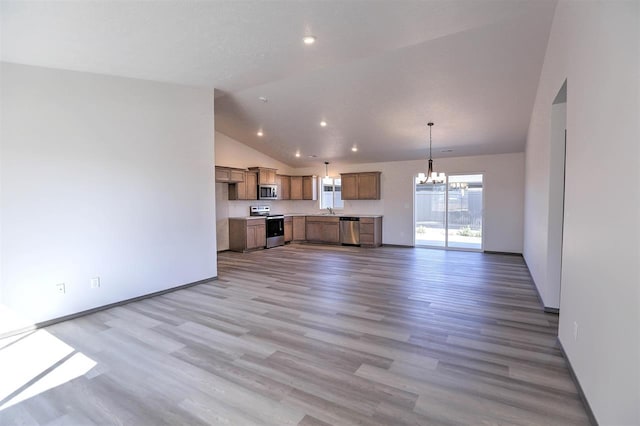 unfurnished living room with sink, hardwood / wood-style floors, lofted ceiling, and a notable chandelier