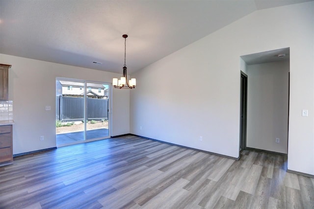 unfurnished dining area with a chandelier, light hardwood / wood-style floors, and vaulted ceiling