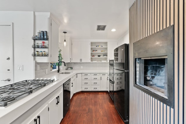 kitchen with white cabinets, black appliances, sink, hanging light fixtures, and tasteful backsplash