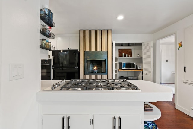 kitchen featuring black appliances, dark hardwood / wood-style floors, and white cabinets