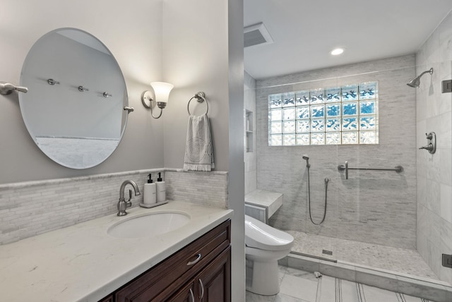 bathroom with toilet, vanity, and tiled shower