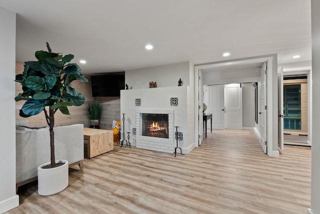 living room featuring light hardwood / wood-style flooring and a brick fireplace