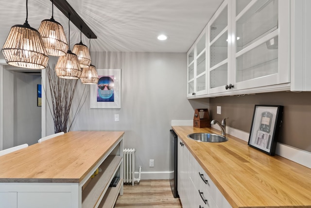 kitchen with sink, white cabinets, hanging light fixtures, and wood counters