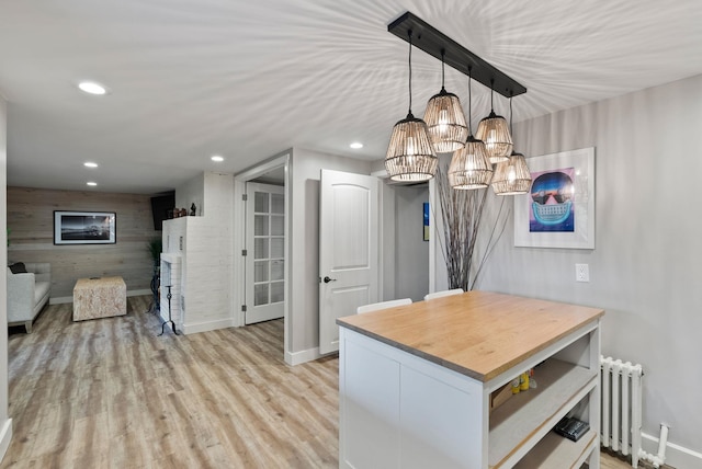 kitchen with wood counters, an inviting chandelier, radiator heating unit, light hardwood / wood-style floors, and hanging light fixtures