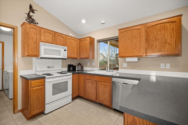 kitchen with white appliances, sink, washer and dryer, light tile patterned floors, and lofted ceiling