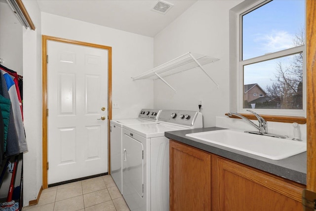 washroom with light tile patterned flooring, sink, and washing machine and clothes dryer