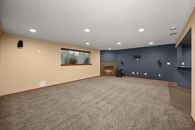 interior space featuring carpet floors, a textured ceiling, a tile fireplace, and ornamental molding