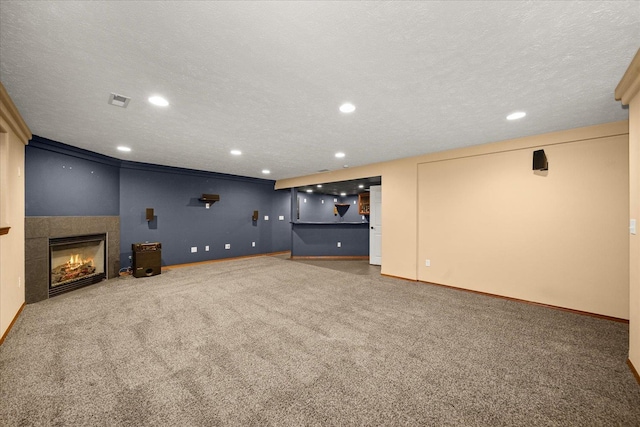 unfurnished living room with carpet, a textured ceiling, and a tile fireplace