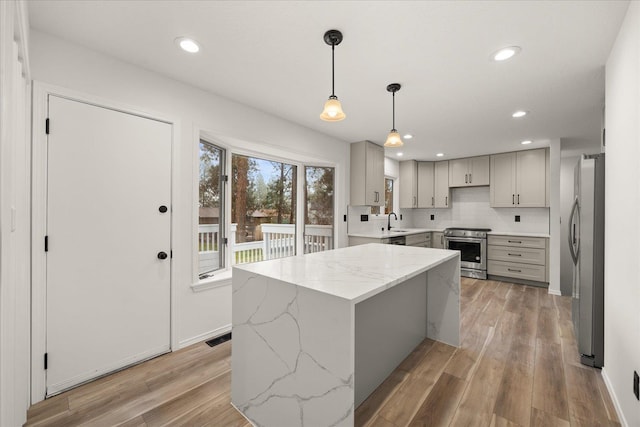 kitchen featuring light stone counters, a center island, decorative light fixtures, and appliances with stainless steel finishes