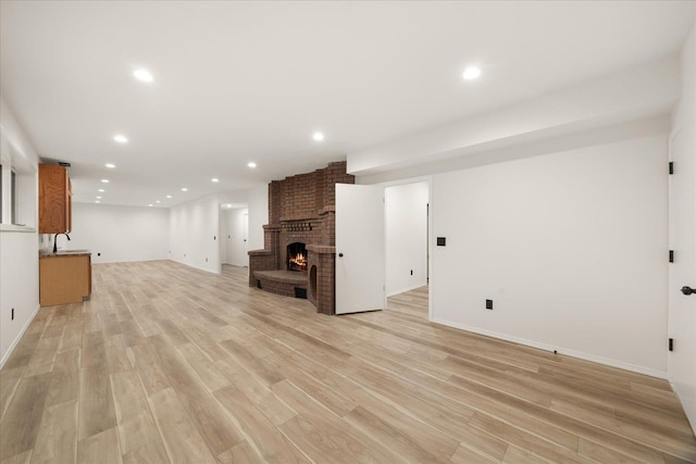 unfurnished living room with light hardwood / wood-style floors, sink, and a fireplace