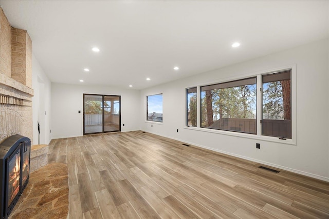 unfurnished living room with light wood-type flooring and a wood stove