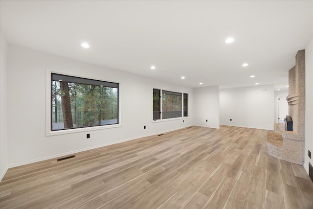 unfurnished living room with a fireplace and light wood-type flooring