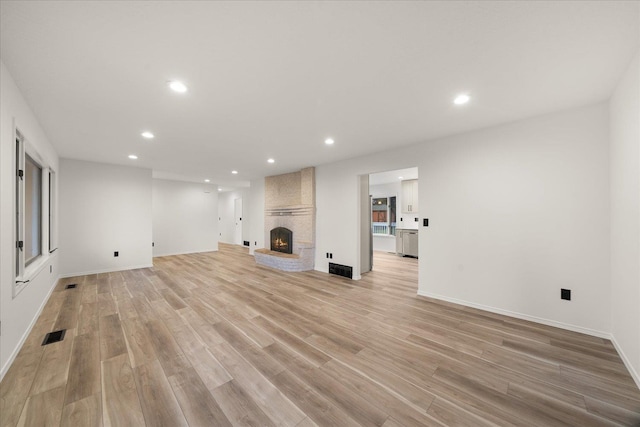 unfurnished living room with light wood-type flooring and a brick fireplace