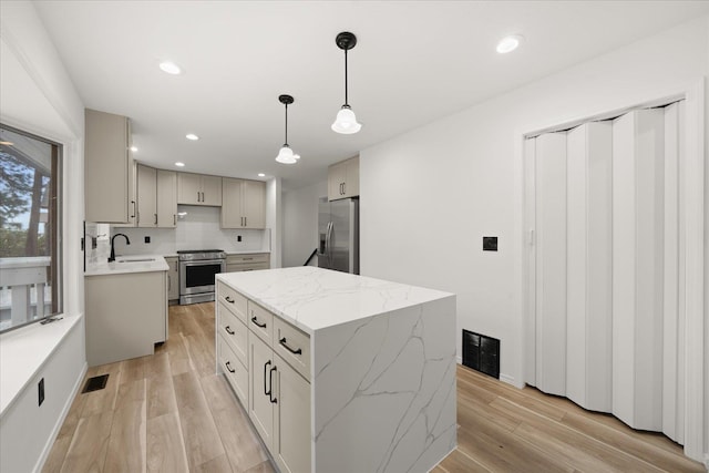 kitchen featuring hanging light fixtures, stainless steel appliances, tasteful backsplash, light hardwood / wood-style floors, and a kitchen island