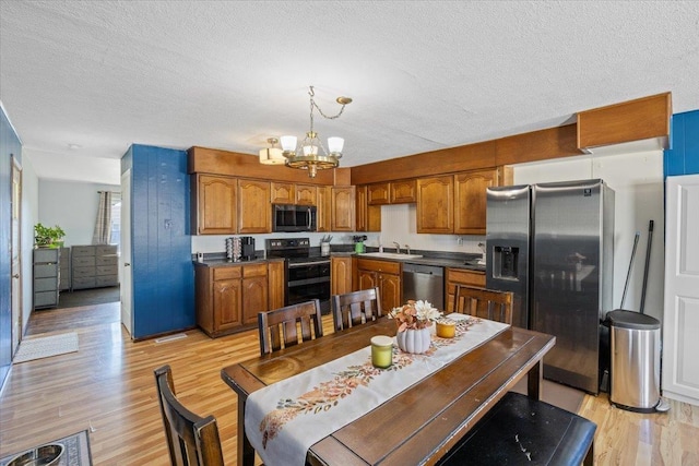 kitchen featuring stainless steel appliances, sink, an inviting chandelier, light hardwood / wood-style floors, and hanging light fixtures