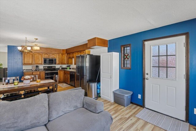 living room with a textured ceiling, light hardwood / wood-style flooring, a notable chandelier, and sink